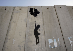 Banksy grafitti of girl floating up with baloons on the Israel palistine wall